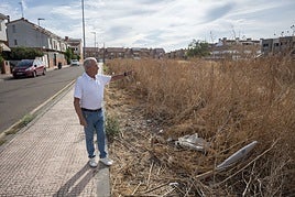 Fernández señala la altura de la maleza que hay frente a su vivienda.