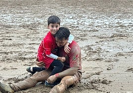 El capitán Nene, sobre el barro abrazado a un chaval al finalizar un encuentro.