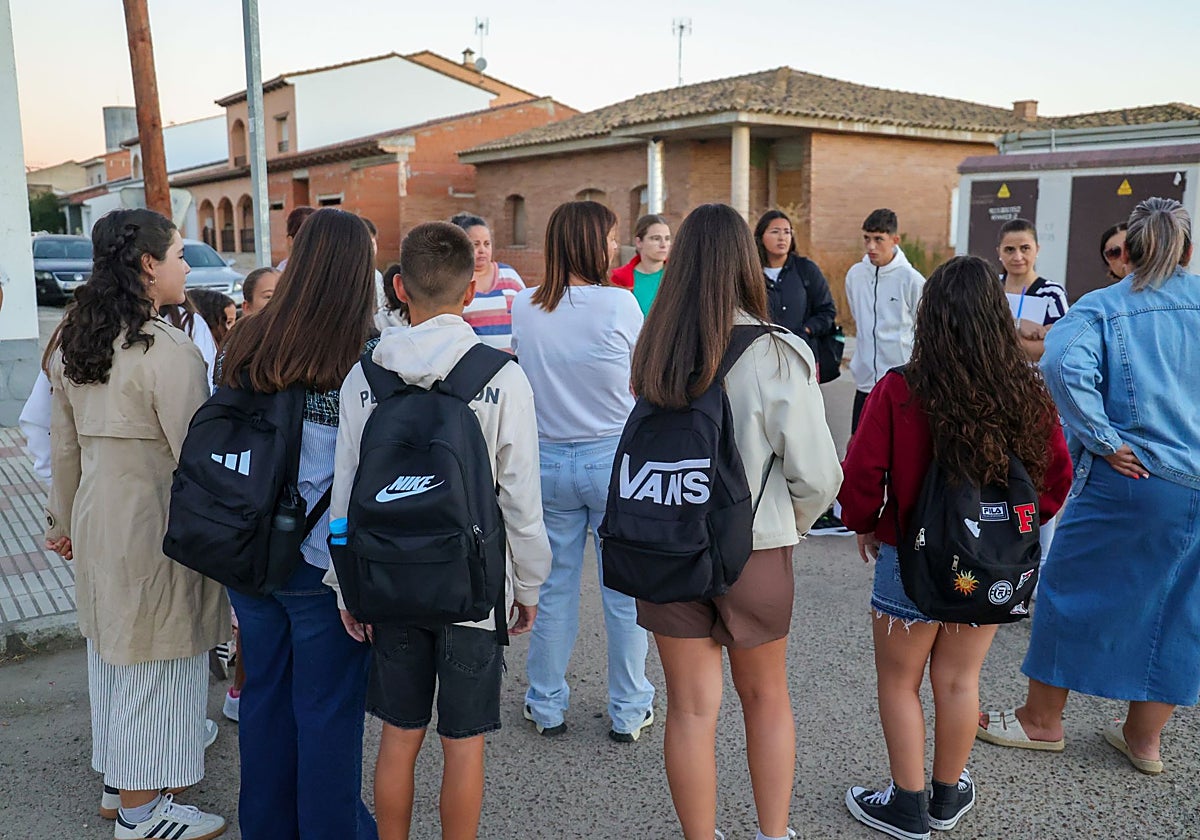 Padres y alumnos esperando en una parada de autobús en el primer día de clase de este curso.