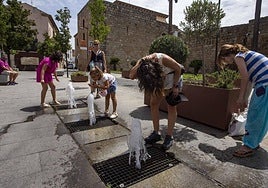 Unos turistas se refrescan junto a unas fuentes en el entorno de la Alcazaba de Mérida.