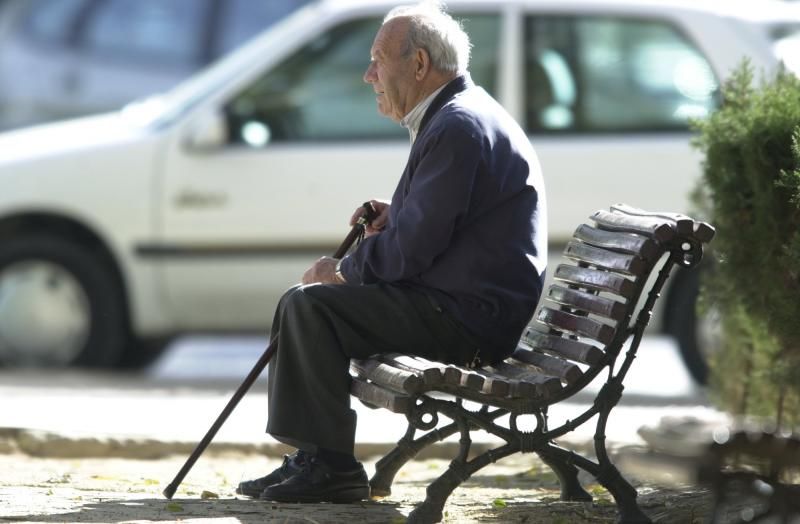 Persona mayor sentada en un banco.