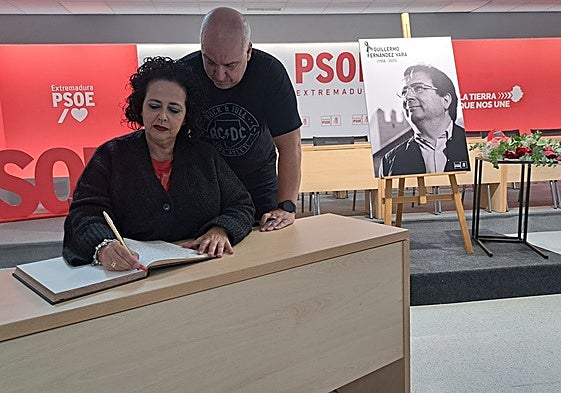 Mercedes Custodio y su marido, Francisco Javier Carreras, firman esta mañana en el libro de condolencias habilitado por el PSOE extremeño en su sede regional, en Mérida.