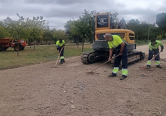 Un grupo de trabajadores repone tierra en el parque de La Isla, junto al río Guadiana.