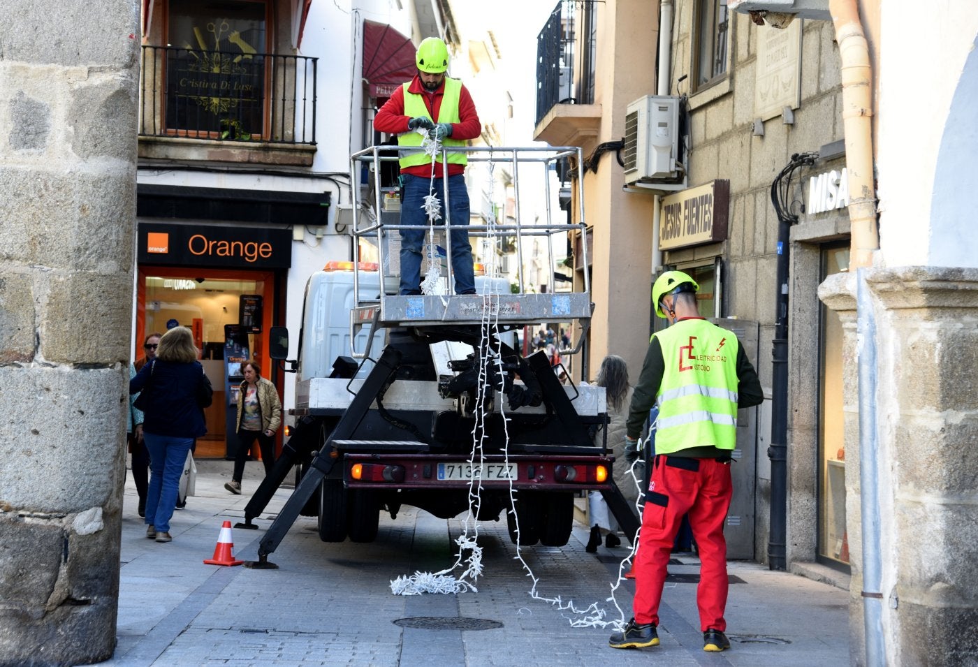 Empleados de la empresa adjudicataria colocan la iluminación a la entrada de la calle del Sol.