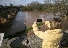 Imagen de archivo de una mujer fotografiando la crecida del río Guadiana a su paso por Mérida.