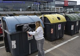 Una joven deposita una bolsa de basura en un contenedor de la carretera de Sevilla este miércoles.