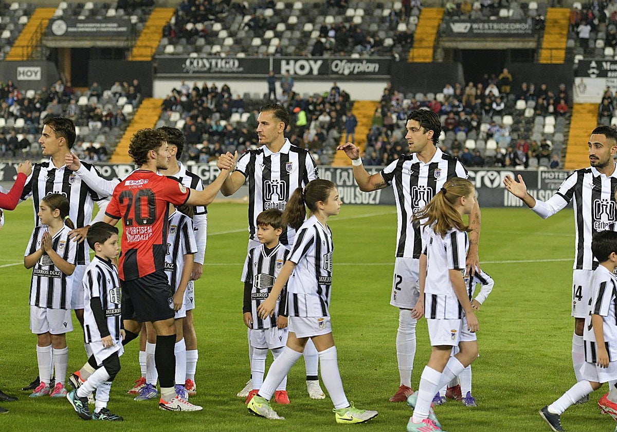 Los chavales de la cantera saltan al césped de la mano de los jugadores del Badajoz antes del comienzo de los partidos.