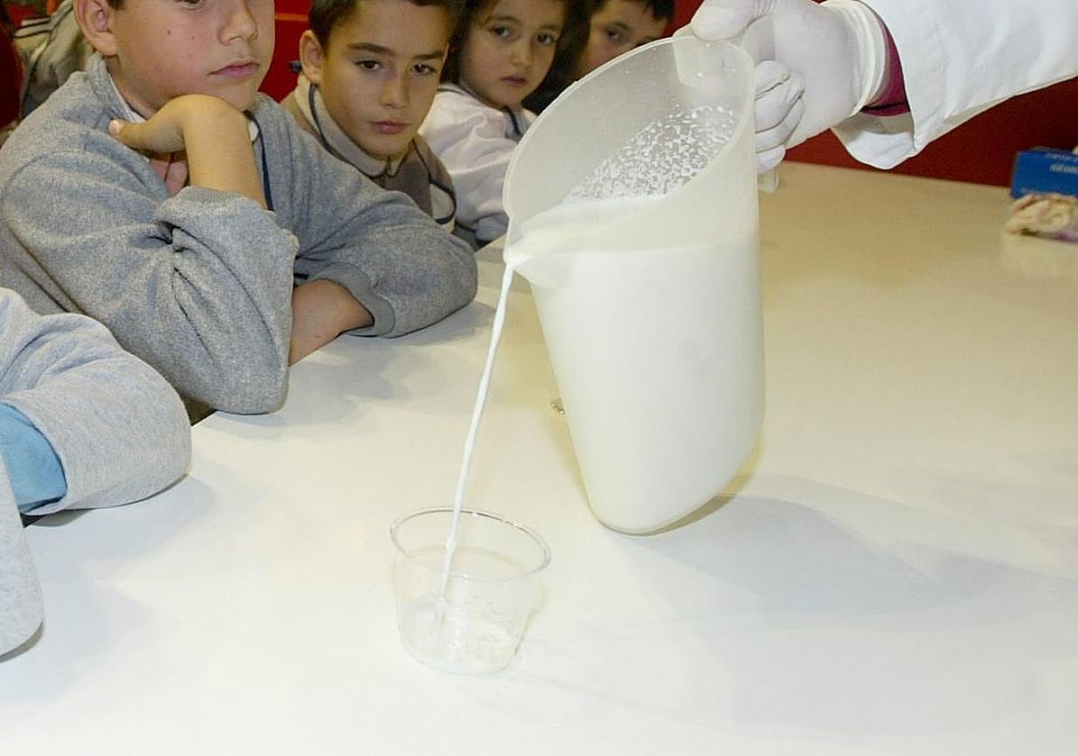 Alumnos de un colegio observan cómo un monitor sirve un vaso de leche.
