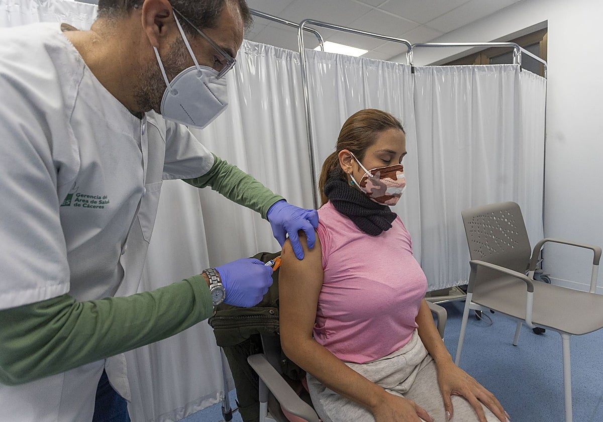 Un enfermero vacuna a mujer de la gripe en Cáceres.