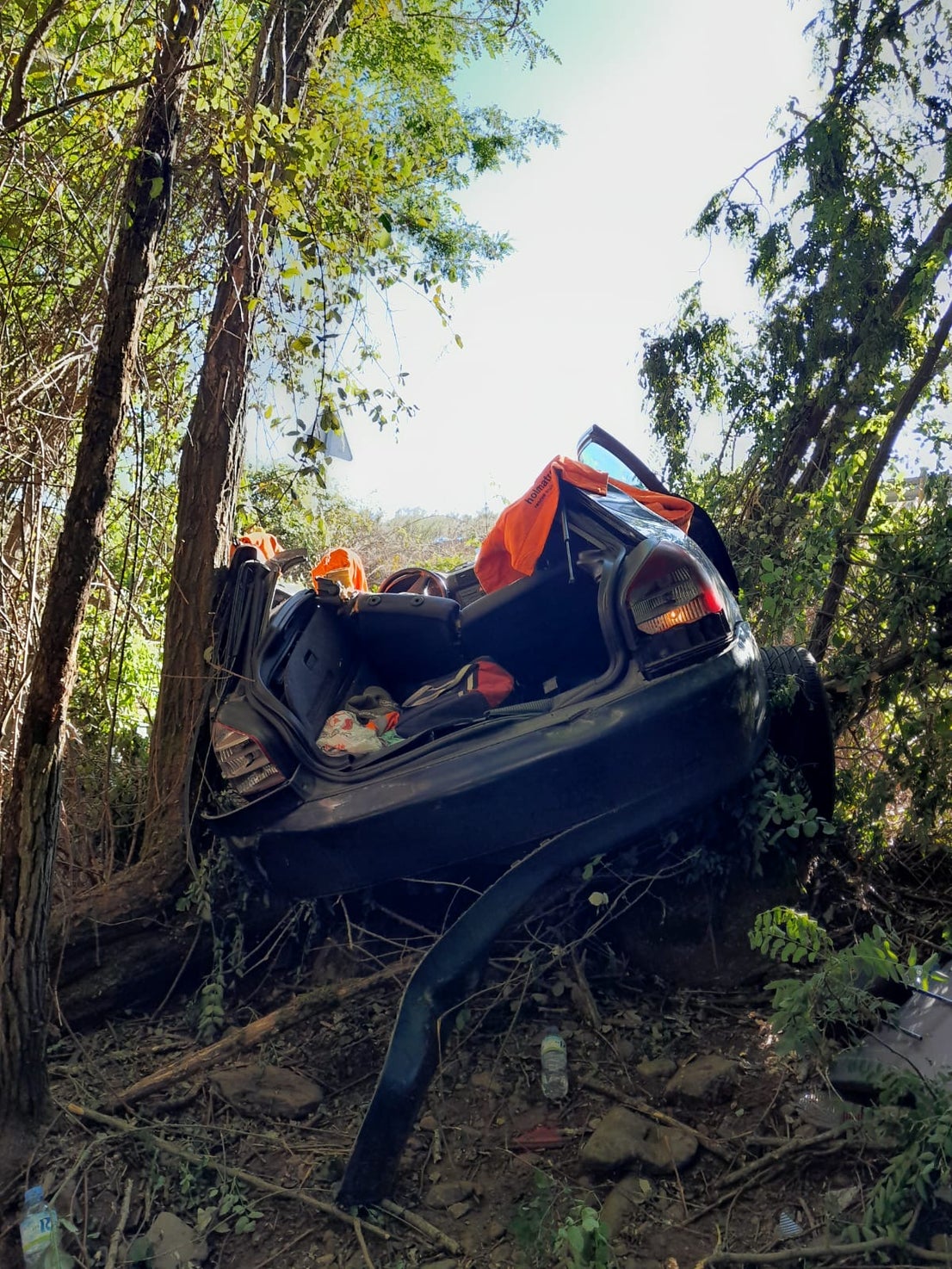 Los bomberos trabajan para rescatar a los dos ocupantes del turismo, que se ha salido de la vía y ha caído por un terraplén.