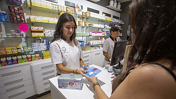 Una farmecéutica dispensa mascarillas y un test de covid a una clienta este jueves en Cáceres.