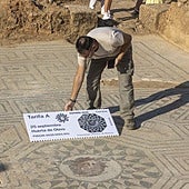 Un trabajador del Consorcio, con una réplica en grande del nuevo sello de Correos con la Medusa de Huerta de Otero, sobre el propio yacimiento.