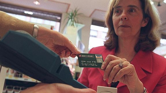 Una mujer paga con tarjeta en un comercio.