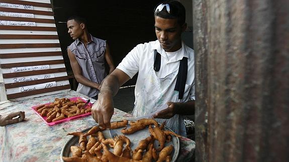 Dos cubanos preparan comida tradicional en La Habana.