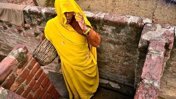 Una mujer india limpia una letrina.