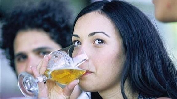 Una chica bebe cerveza. 