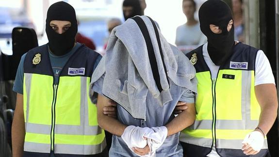 El detenido con la cabeza tapada, tras concluir el registro de su casa.  