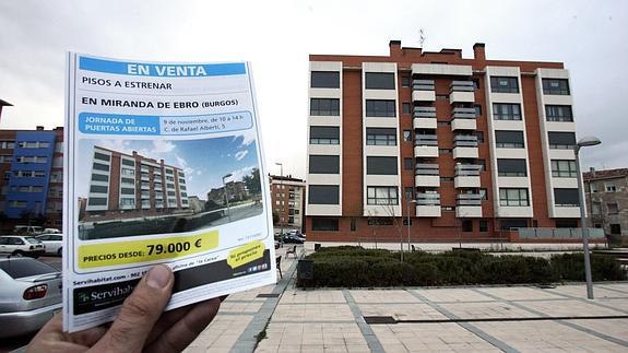 Una persona muestra el folleto de unos pisos a la venta. 