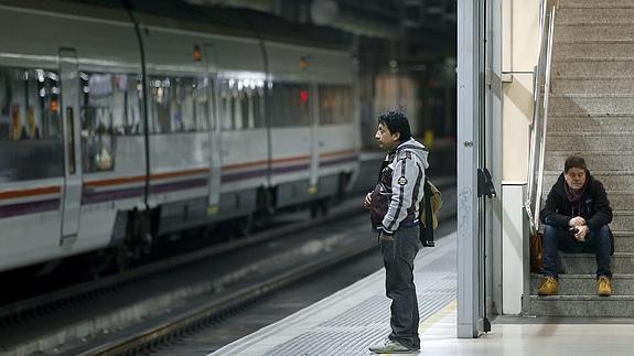 Dos viajeros esperan en un anden de la estación de Sants de Barcelona. 