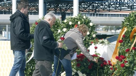 Varios familiares dejan rosas rojas en el monumento de recuerdo en el aeropuerto de El Prat.