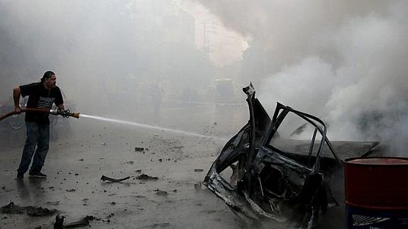Los equipos de emergencia apagan el fuego provocado por el coche bomba. 