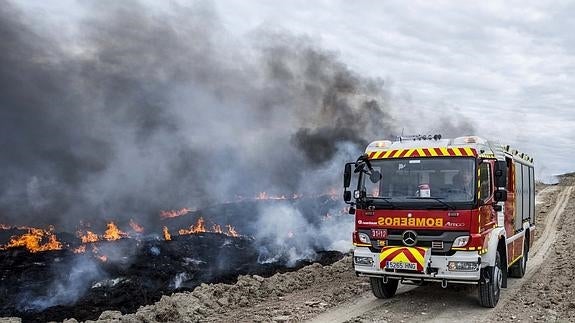 Un camión del cuerpo de bomberos pasa junto a los neumáticos que arden en Seseña. 