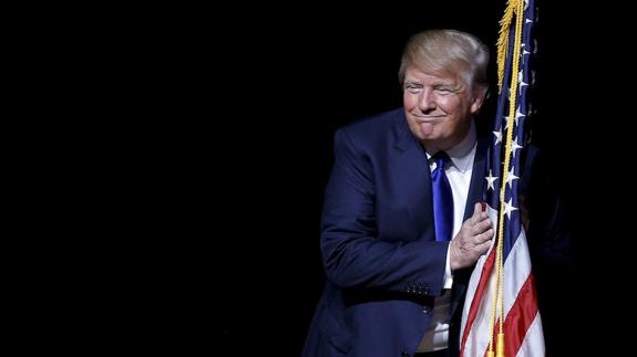 Donald Trump abrazando una bandera de EEUU.