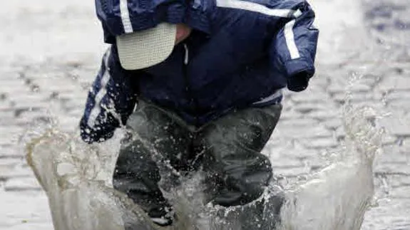 Un niño chapotea en un día lluvioso.