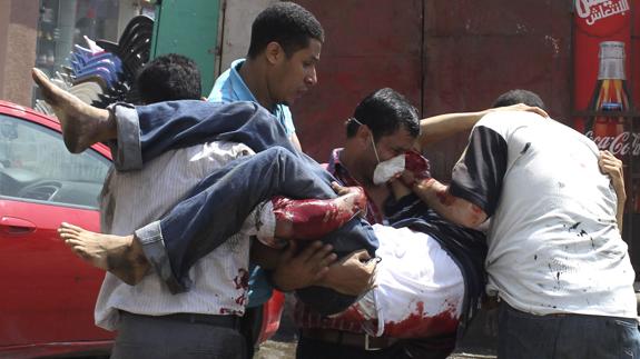 Varias personas atienden a uno de los heridos durante el desmantelamiento por el régimen militar egipcio de la Plaza Al -Nahda en 2013.