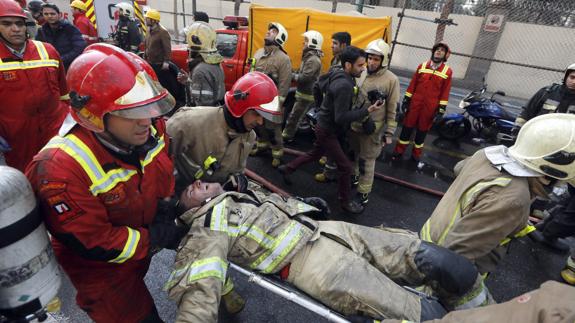 Bomberos iraníes trasladan a un compañero que lograron rescatar tras quedar atrapado entre los escombros. 