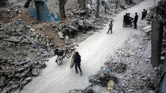 Varias personas buscan sus pertenencias entre los escombros en Douma.
