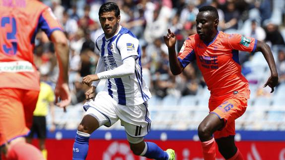 El delantero mexicano de la Real Sociedad Carlos Vela (i) disputa un balón con el centrocampista costamarfileño del Granada Victorien Angban (d).