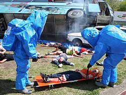 Personal con traje estanco recogiendo a una una de las víctimas. / ANDY SOLÉ