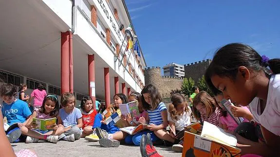 Alumnos de primaria en una sesión de lectura en el patio de un colegio placentino