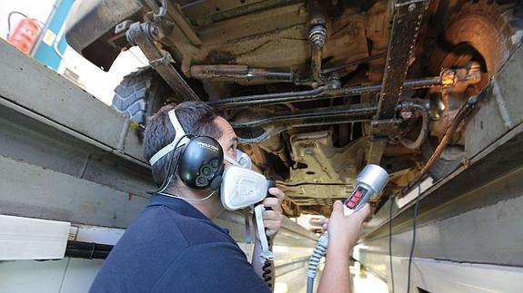 Un operario del centro de Cáceres inspecciona un vehículo