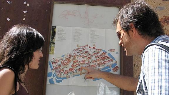 Dos turistas consultan el plano del callejero turístico de Cáceres, para orientarse.