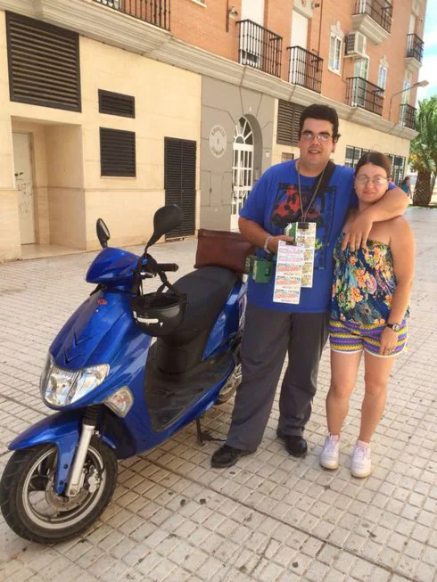 Sergio y su novia junto a la moto con la que vende cupones. :: fh