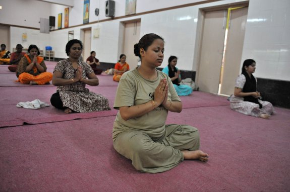 Un grupo de mujeres practican yoga en Hyderabad (India). En el recuadro, el maestro Iyengar. :: NOAH SEELAM / afP