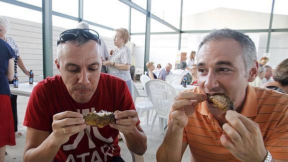 Dos participantes degustan tenca frita en uno de los recintos habilitados en Hinojal.
