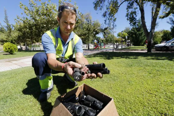 Un trabajador de la UTE de jardines muestra una caja llena de elementos de riego destrozados por los vándalos. :: andy solé