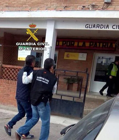 Un agente conduce a uno de los detenidos a un cuartel de la Guardia Civil