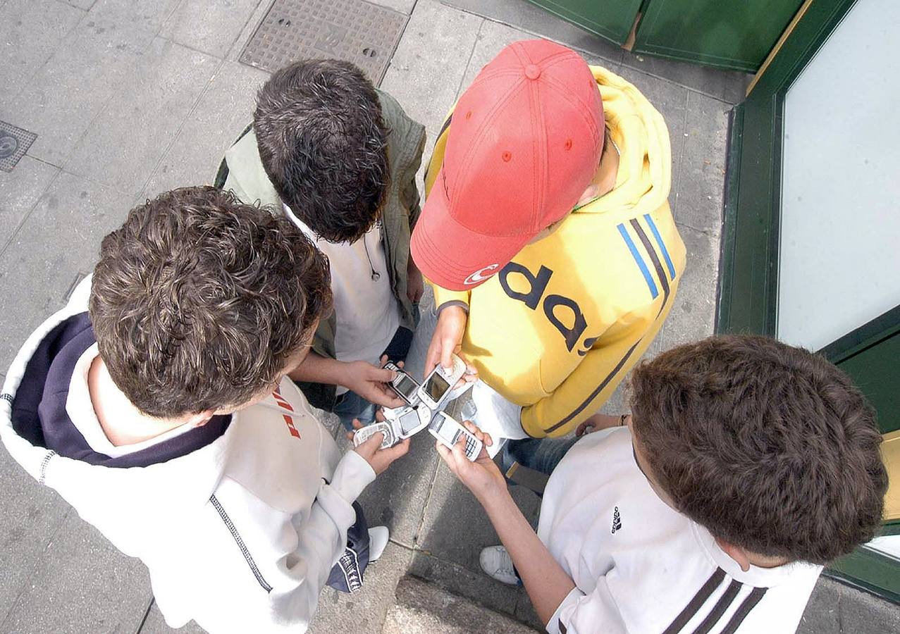 Varios escolares consultan sus teléfonos móviles a la salida de clase