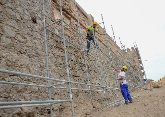 Dos obreros instalan el andamio que rodea el tramo de muralla que será recuperado. :: c. moreno