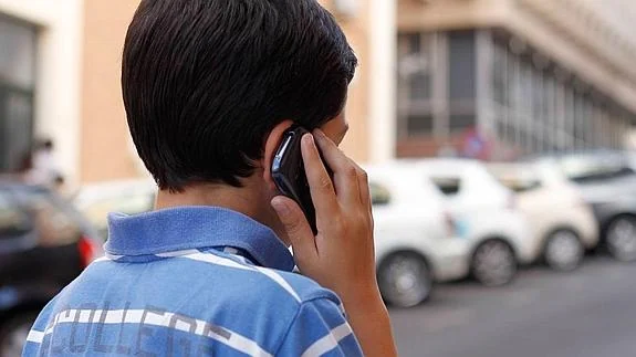 Un niño cacereño habla por su teléfono móvil.