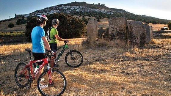 Dos jóvenes ciclistas frente al dolmen de magacela, uno de los atractivos de la ruta Transerena. 