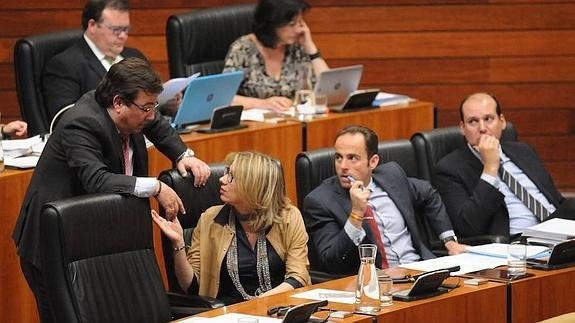 Guillermo Fernández Vara habla con Cristina Teniente, ante la mirada de Juan Parejo y Luis Alfonso Hernández Carrón, durante el pleno de esta tarde 
