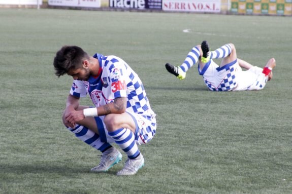 Dos jugadores del Arroyo se lamentan sobre el césped del Municipal al termino del encuentro de ayer. :: Lorenzo Cordero