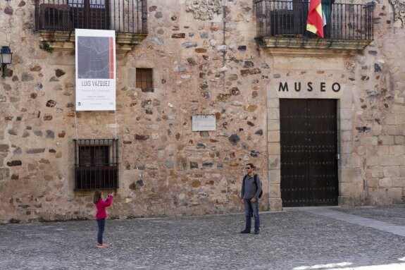 Un turista se hace una fotografía junto a la puerta cerrada del Museo de Cáceres. :: Armando Méndez