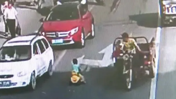 Un niño circula con su coche de juguete por una carretera