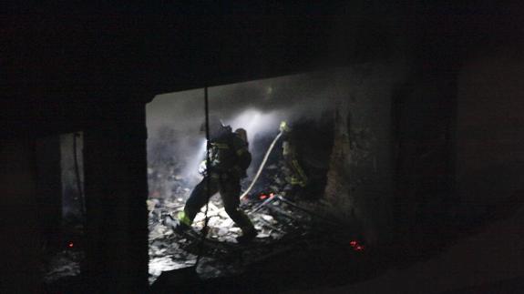 Un bombero en plena extinción del fuego originado tras la explosión, que hizo desaparecer las paredes del piso. :: 